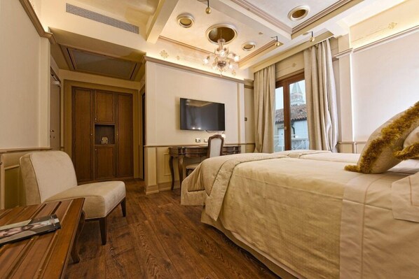 A hotel room with a large bed, a desk with a chair, a television, and a wooden table. - Hotel Monaco & Grand Canal (Venice)