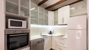 A modern kitchen with white cabinetry, a built-in microwave, a dishwasher, and a refrigerator. - Catedral - Unik Vacation (Tarragona)