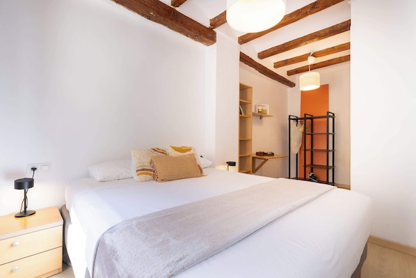 A bedroom with a large bed, a bedside table, a lamp, a wardrobe, and a ladder against the wall.