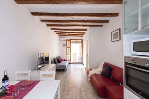 A compact living space with a dining area, a sofa, a TV, and an oven.
