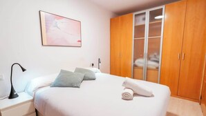 A bedroom with a bed, pillows, a nightstand, a lamp, a wardrobe, and a painting on the wall. - Ripoll Old Town - Unik Vacation (Tarragona)