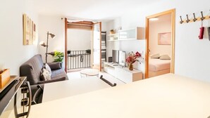 A modern living room with a sofa, dining table, and a TV. - Ripoll Old Town - Unik Vacation (Tarragona)