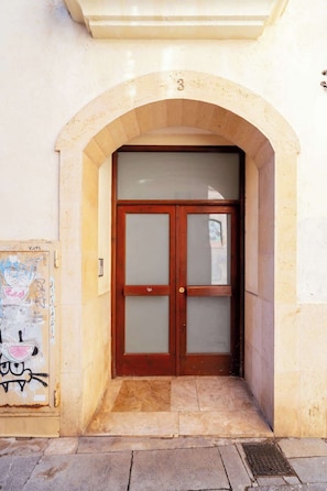 Une entrĂ©e dâimmeuble avec une porte en bois et un arc en pierre.