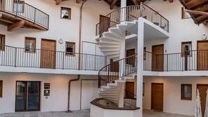 A multi-story building with a central spiral staircase, wooden balconies, and stone flooring.