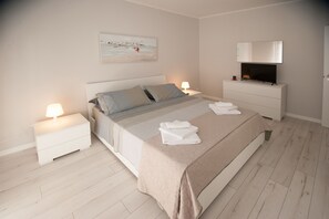 Ein Schlafzimmer mit einem Bett, Nachttischen, einem Fernseher und einem Gemälde an der Wand.