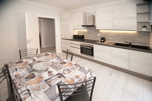 A modern kitchen with light wood cabinets, a built-in oven, and a stainless steel sink.