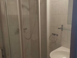A glass-enclosed shower with a handheld showerhead and a glass door.