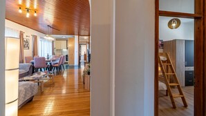 Uma sala ampla com piso de madeira, uma mesa de jantar com cadeiras, um sofá e uma escada no canto.