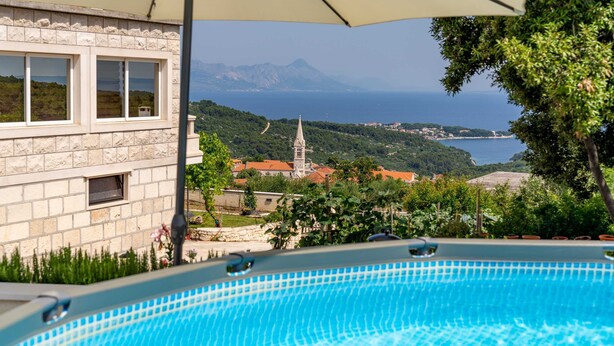 Piscina com vista para uma paisagem montanhosa e uma igreja.