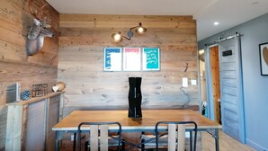 A dining area with a wooden table and chairs, a mounted deer head, and two framed signs on the wall. - Renovated apartment for 4, near slopes in Pra Loup (Pra-Loup)