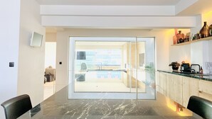 A modern kitchen with a marble countertop, a glass door leading to a balcony, and a view of the cityscape. - Beautiful Specious Design Duplex Penthouse With sea View (Knokke-Heist)