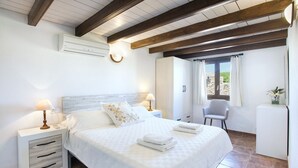 Ein Schlafzimmer mit einem Bett, Nachttischen, einem Sessel, einem Schreibtisch und einem Fenster.