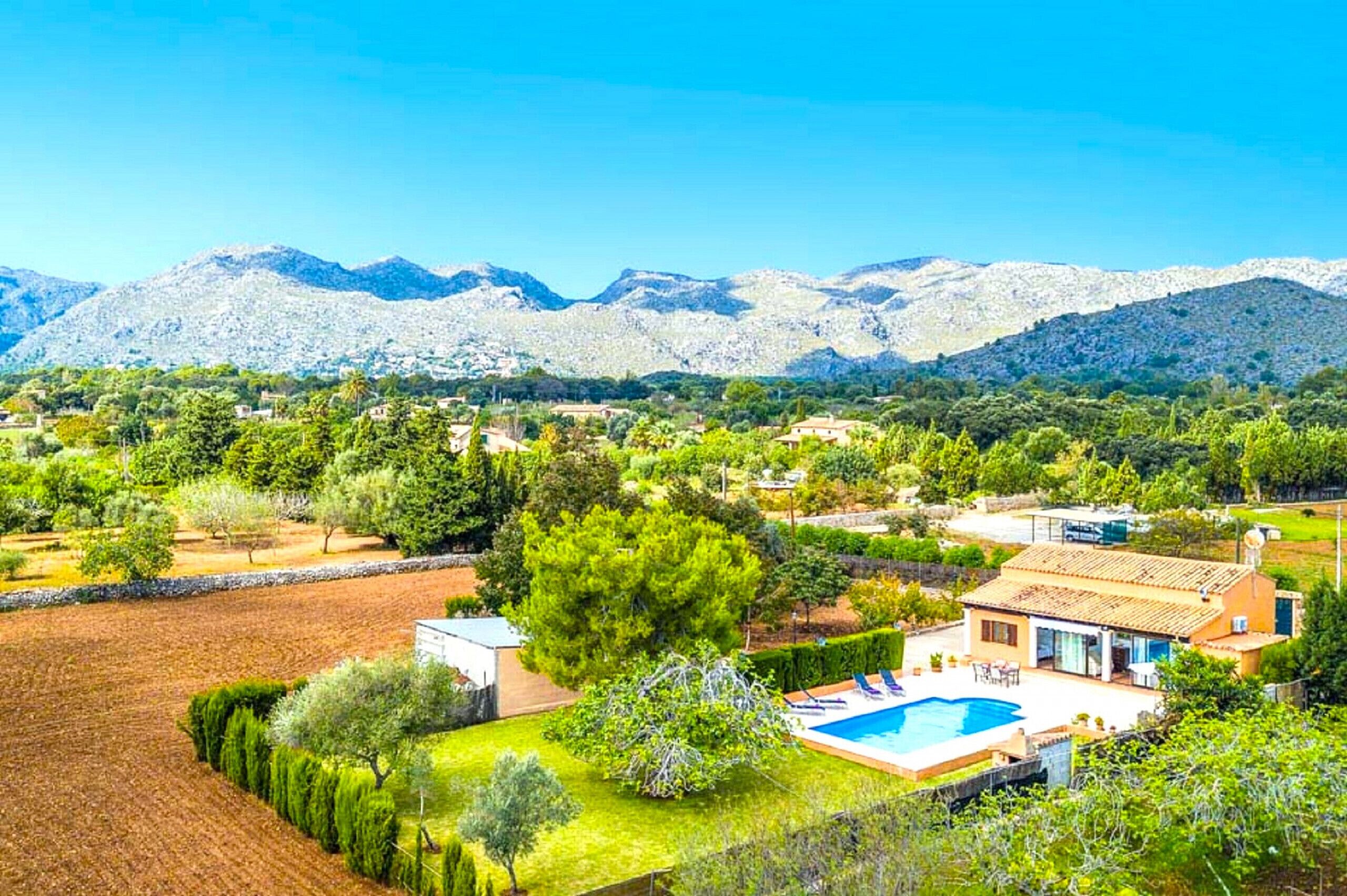 A residential area with a pool, houses, and mountains in the background.