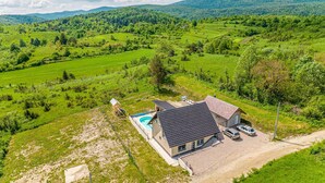 Une maison avec une piscine, entourée de champs verdoyants et de collines.