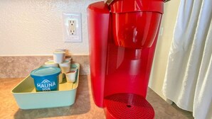 A coffee maker, a Mauna Loa container, and a tray with cups on a countertop.