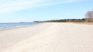 A wide sandy beach with a calm sea and a distant shoreline.