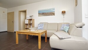 A living room with a sofa, a wooden table, a lamp, and a painting on the wall.