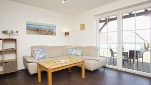 A living room with a sofa, a wooden table, a wall clock, and a painting.