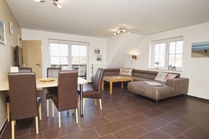 A modern living room with a dining area, a sofa, a coffee table, and a TV.