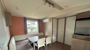 Et kompakt tekøkken med komfur, et spisebord med stole og en indbygget bænk med opbevaring.