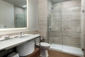 A modern bathroom with a glass-enclosed shower, a white sink, and a toilet.