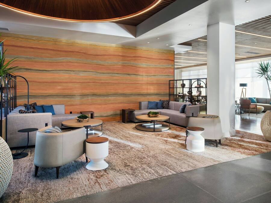 A modern lobby with sofas, coffee tables, and a large abstract mural on the wall.