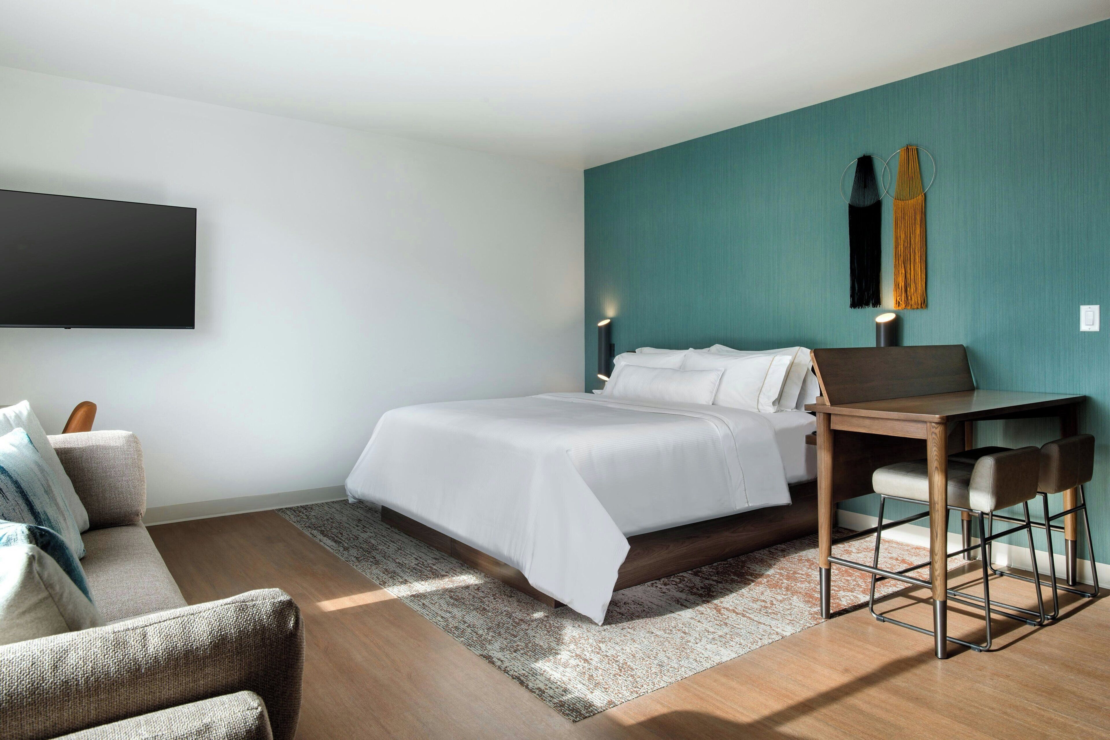 Una habitación de hotel moderna con cama, escritorio y silla.