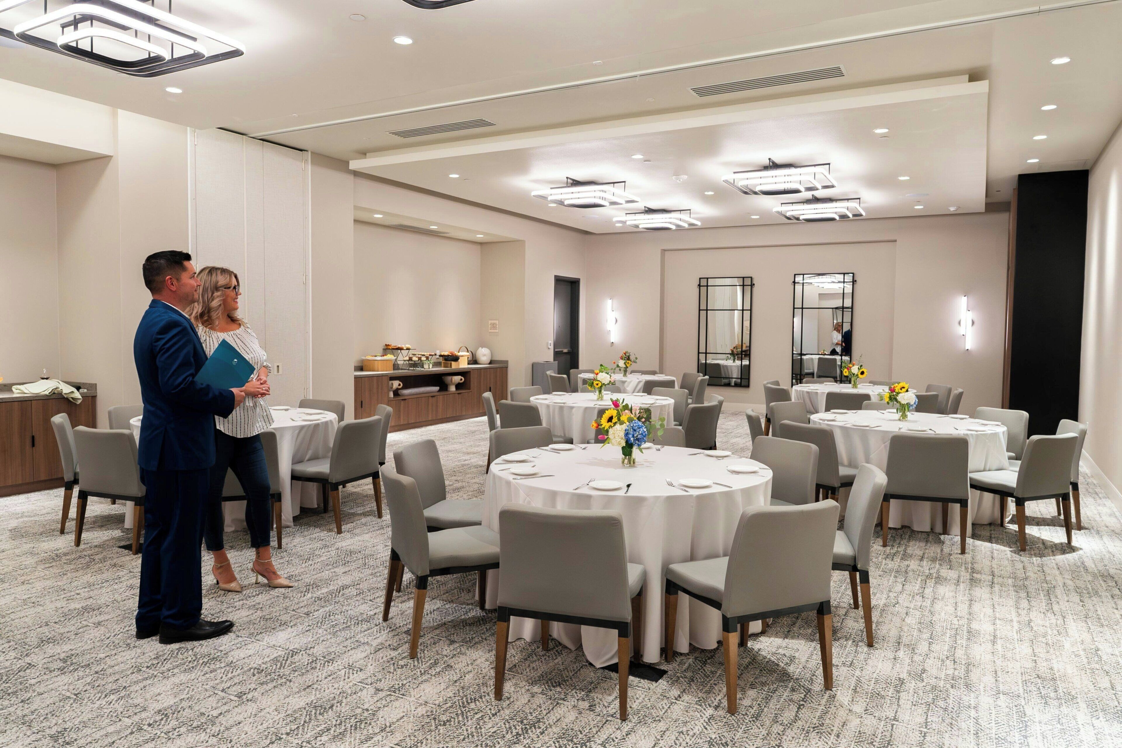 A conference room with round tables, chairs, and a carpeted floor.