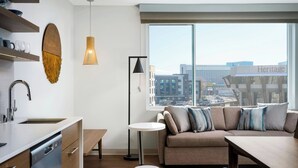 Un apartamento moderno con cocina, comedor, sofá y un amplio ventanal con vistas a la ciudad.