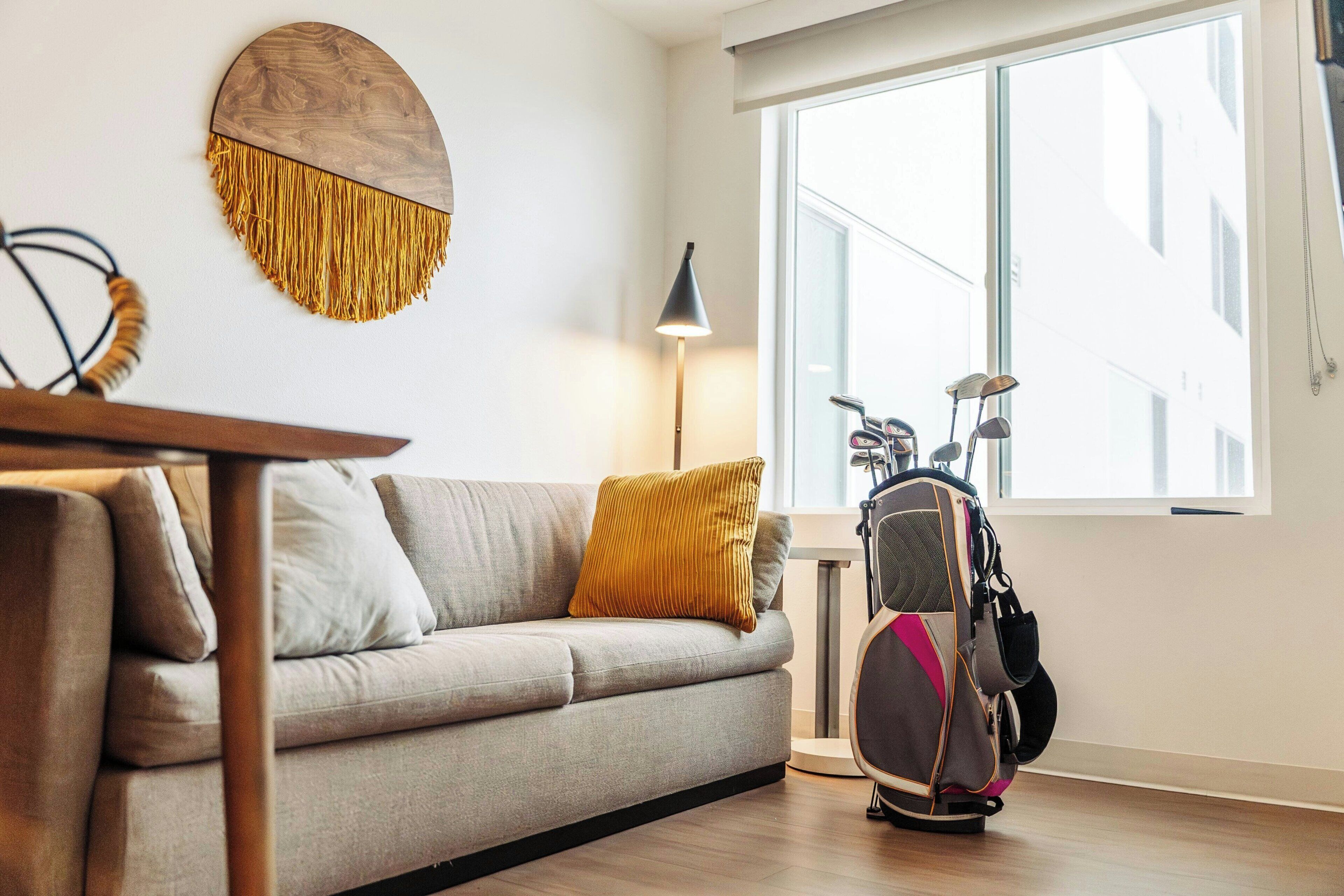 A modern living room with a sofa, a round wall decoration, a lamp, and a stroller.