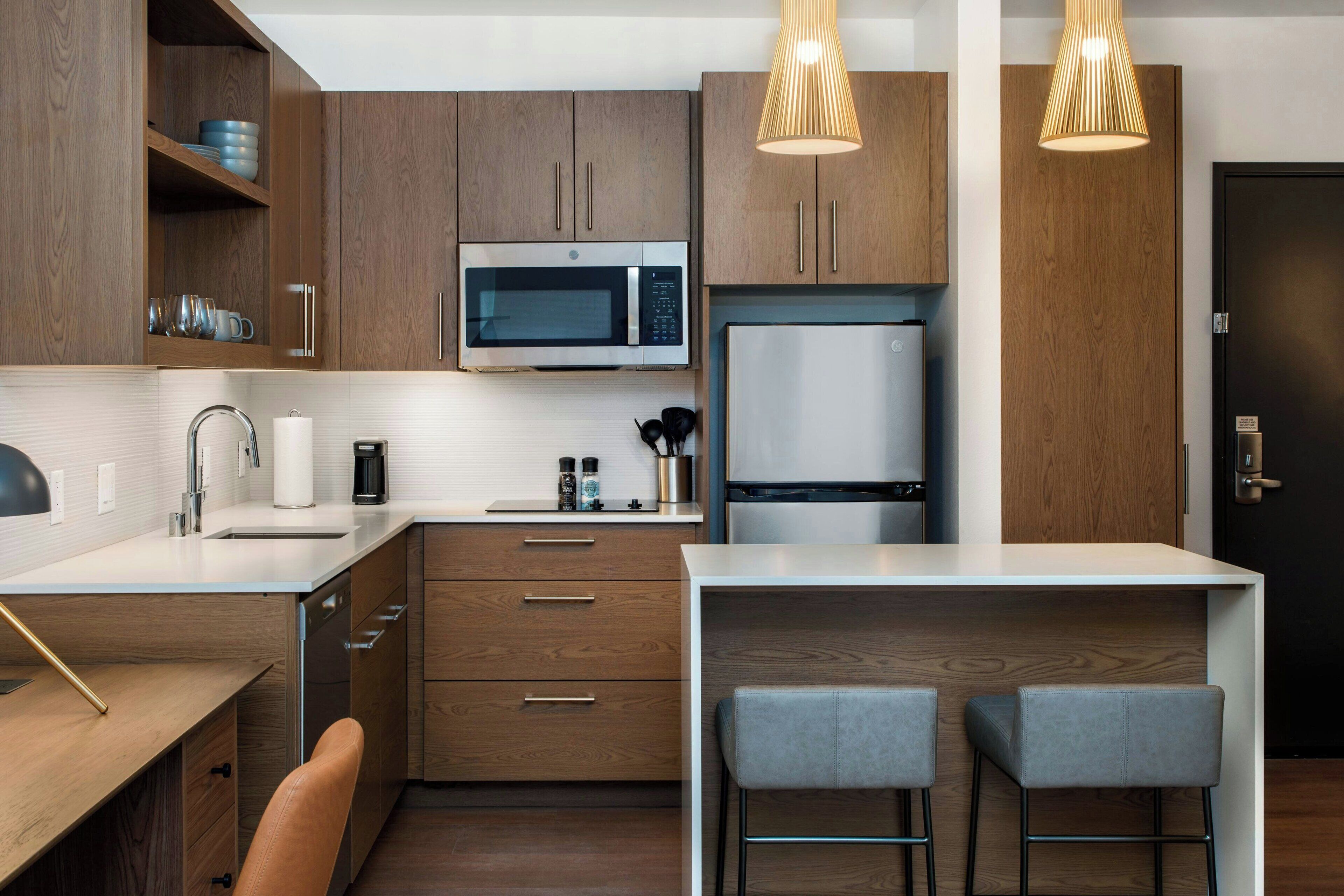 A modern kitchen with wooden cabinets, stainless steel appliances, and a bar area with stools.