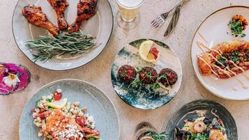 Uma mesa com diversos pratos, incluindo frango grelhado, salada e um croissant.
