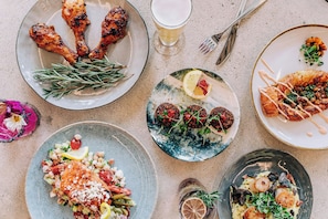 A table with various dishes, including grilled chicken, salad, and a croissant.