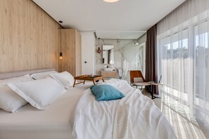 A modern hotel room with a large bed, a desk with a laptop, a bathroom with a marble wall, and large windows with sheer curtains. - Villa Basina is luxury and privacy in picturesque settings on excellent location (Vrboska)