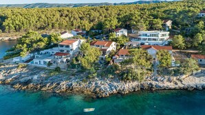 Un villaggio costiero con case costruite su terreno roccioso, affacciato su un mare cristallino e blu.