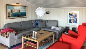A living room with a grey sectional sofa, a red armchair, a wooden coffee table, and a colorful striped rug. - Beautiful home in Farsund with WiFi (Farsund)