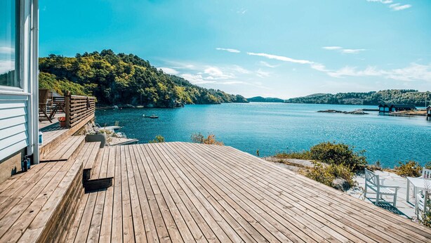 A wooden deck with a view of a calm lake and forested hills. - Beautiful home in Farsund with WiFi (Farsund)