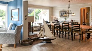 A dining area with wooden tables and chairs, a sailboat model, and a large window with a view of greenery. - Beautiful home in Farsund with WiFi (Farsund)