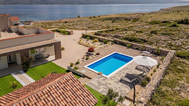 Una casa moderna con piscina, patio y vistas al mar y a las montañas.