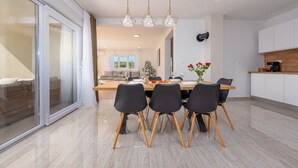 Un comedor moderno con una mesa grande, cuatro sillas y un jarrón de flores.