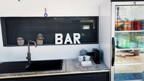 Un espace bar équipé d’un évier, de plantes en pot et d’un réfrigérateur rempli de boissons.