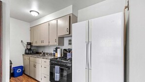 A compact kitchen with a stove, sink, and white refrigerator. - The Tiny Piney - Live. Work. Play. Downtown Green Bay! (Green Bay)