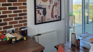 Une cuisine moderne avec un mur en briques, une grande peinture abstraite et une vue sur l’extérieur.