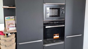 Une petite cuisine équipée d’un four à micro-ondes, d’un four et d’étagères intégrées.