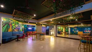 A spacious indoor area with a blue sofa, red chairs, and wooden tables. - Villa Calangute Phase 17 (Calangute)