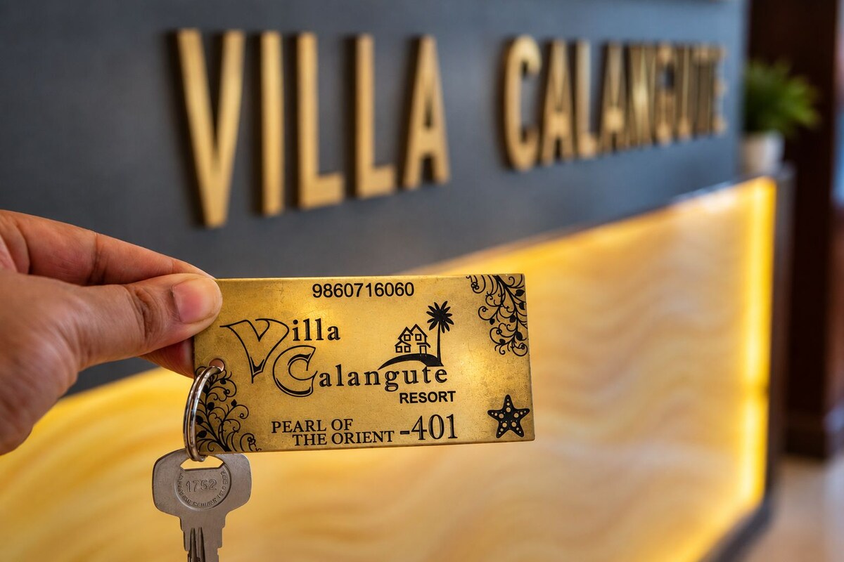 A hand holding a key with a keychain that has a card for Villa Galangute Resort, labeled as 'PEARL OF THE ORIENT - 401'.