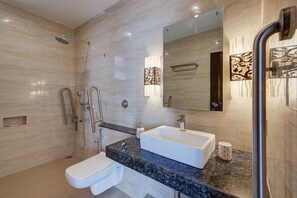 A modern bathroom with a marble wall, a white sink, a large mirror, and a shower area. - Villa Calangute Phase 17 (Calangute)