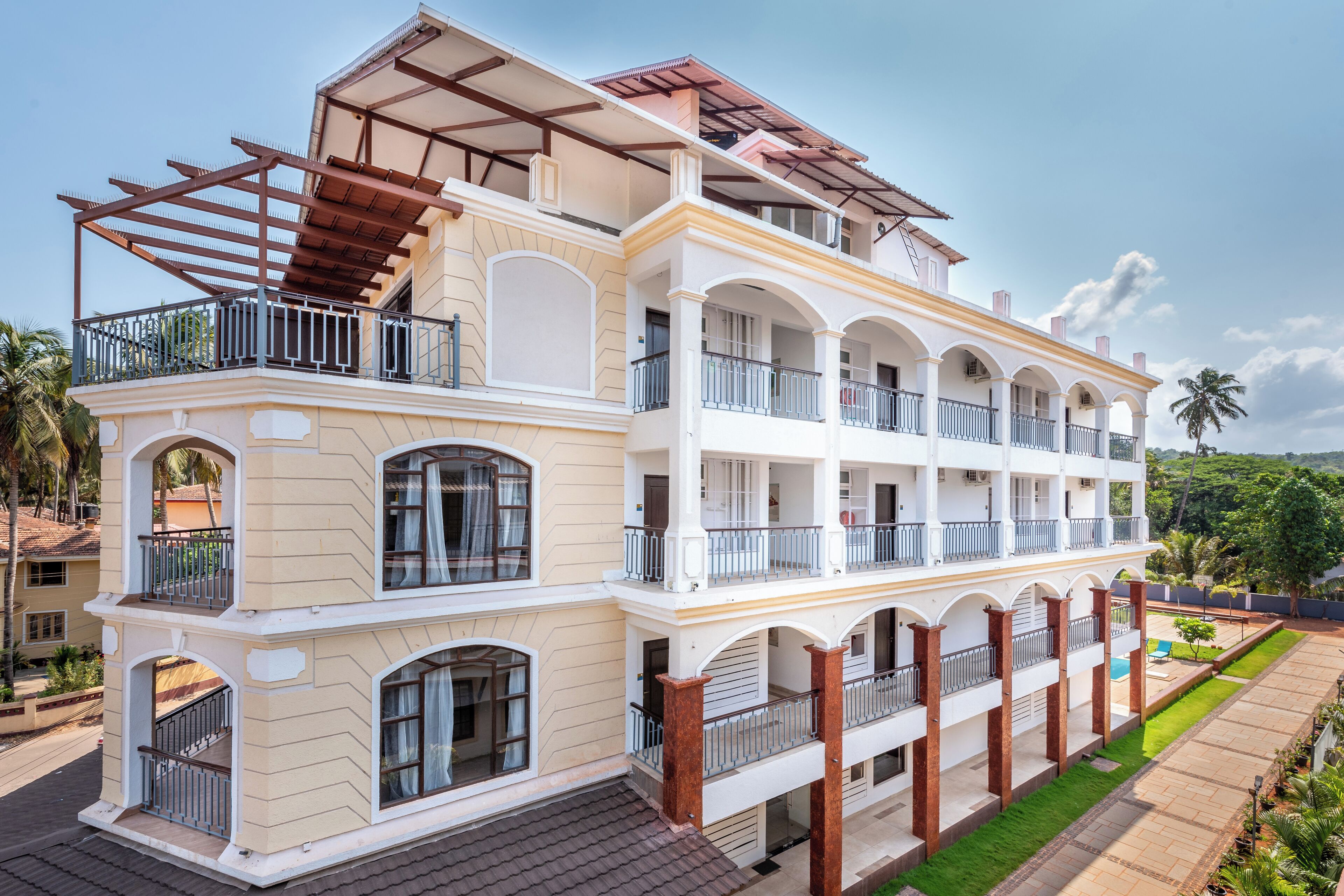 A multi-story hotel with balconies, a covered patio, and a well-maintained lawn.