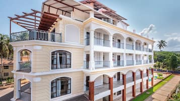 A multi-story hotel with balconies, a covered patio, and a well-maintained lawn.