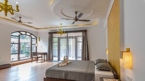 A bedroom with a bed, a chandelier, ceiling fans, and a view through large windows. - Villa Calangute Phase 17 (Calangute)